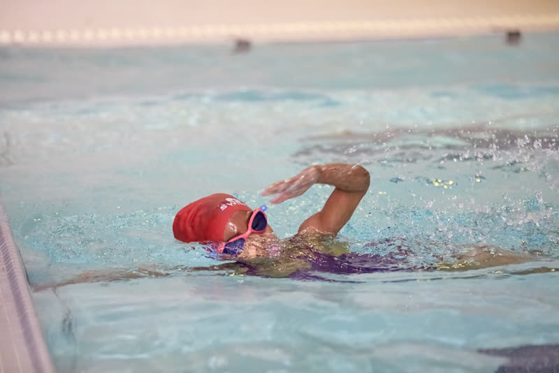 A swimmer in a red cap completing a timed front crawl swim.